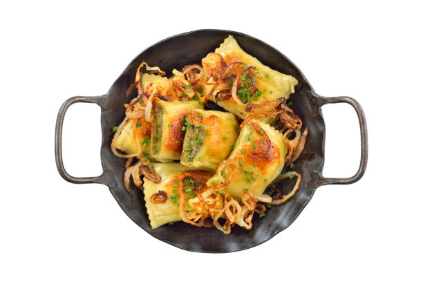 Fried Swabian meat ravioli (so called Maultaschen) with roasted onions, served in an iron frying pan on white background