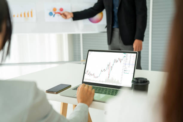 istock Businesswoman in analyze stock market data using laptop computer proficiently at the office while attending a group meeting with business team . 1468325555