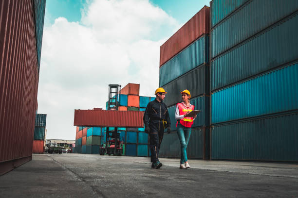 istock Industrial worker works with co-worker at overseas shipping container yard . Logistics supply chain management and international goods export concept . 1468327560