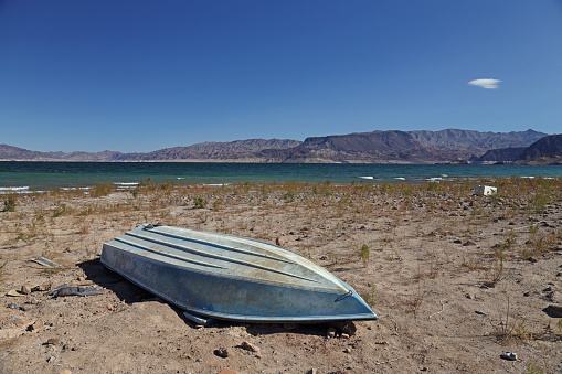 An abandoned boat on the shores of Lake Mead near Las Vegas, Nevada. Like many artifacts, ruins, and even bodies, this boat has now come to light as the shore of Lake Mead is significantly receding. This image has themes of drought, environment, global warming, water, and natural resources themes.