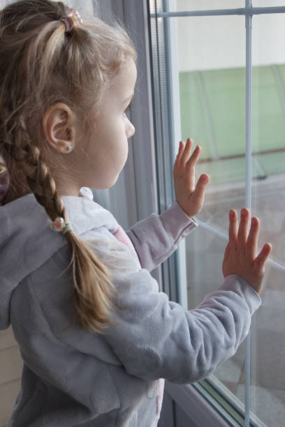 istock Little cute kid looking through the window 1468327960
