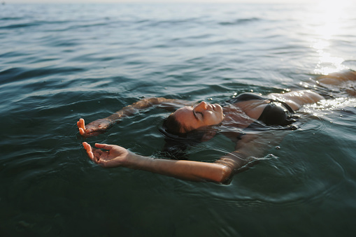 Photo of a mid-adult woman swimming in a sunset