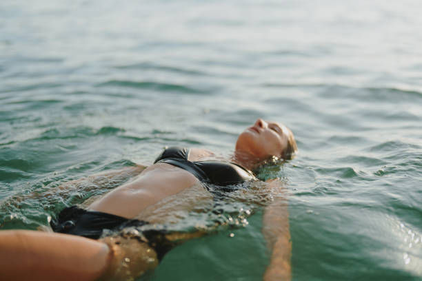 schwimmen bei sonnenuntergang - sea swimming greece women stock-fotos und bilder