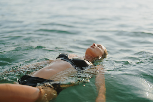 Photo of a mid-adult woman swimming in a sunset