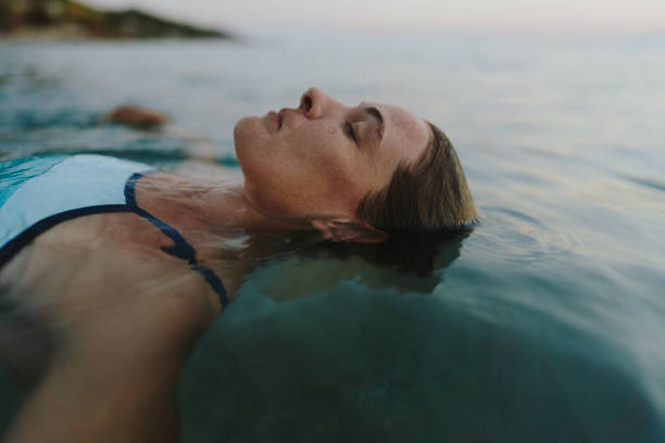 frau im mittleren erwachsenenalter, die im meer schwimmt - sea swimming greece women stock-fotos und bilder