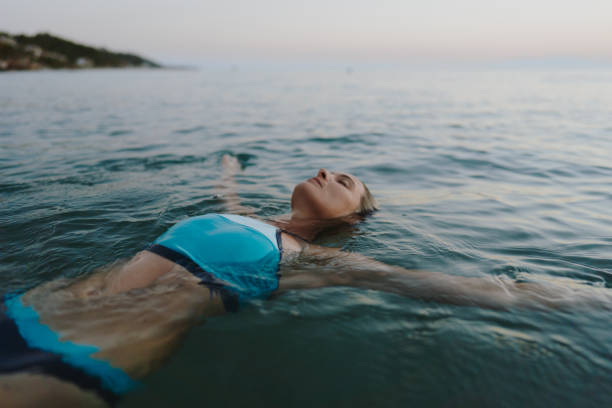frau im mittleren erwachsenenalter, die im meer schwimmt - sea swimming greece women stock-fotos und bilder