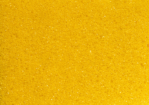 Yellow foam rubber sponge, polygonal pores close-up background wallpaper, uniform texture pattern