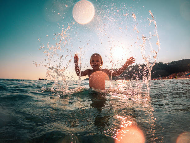istock Smiling Boy Sprinkling Water During a Beach Holiday 1468348237