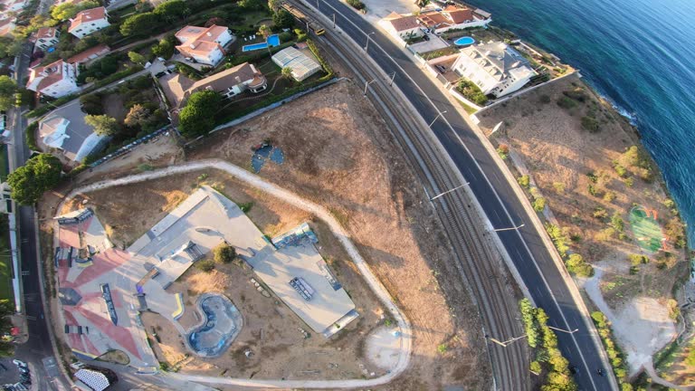 side wide drone shot of Skatepark Parque das Gerações in Cascais Portugal. revealing the empty skate park with training crossing enjoying a wonderful sunrise with amazing orange sunset colors. Estoril