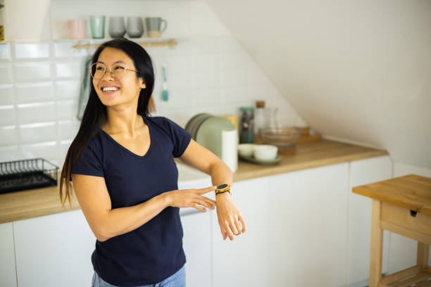 istock Happy Asian young woman using smart watch and adjusting smart home system 1468358376