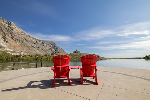 Waterton Lake and Nature Landscape in Waterton Lakes National Park, Alberta, Canada. Two red chairs are close to the lake.