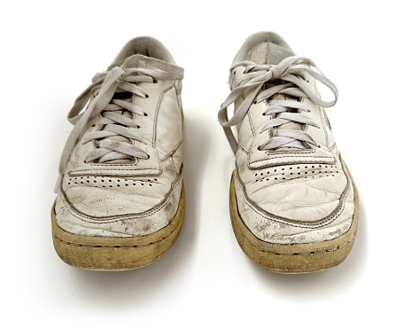 Various angles of a pair of  old vintage generic leather sneakers in heavily worn out condition. Clear-cut on a white seamless background