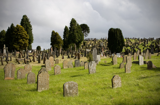 Old cemetery with obsolete bent gravestones below the stormy sky