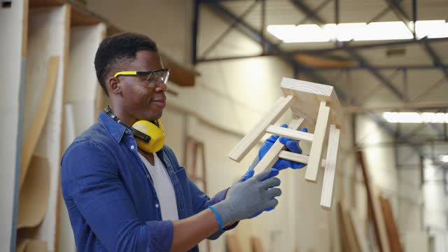 African American male carpenter holding wooden piece while standing smiling.small business concept, craft, hobby
