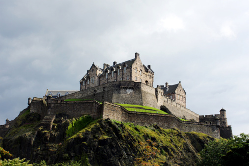 The historical landmark Edinburgh Castle, Scotland, set against a stormy sky.