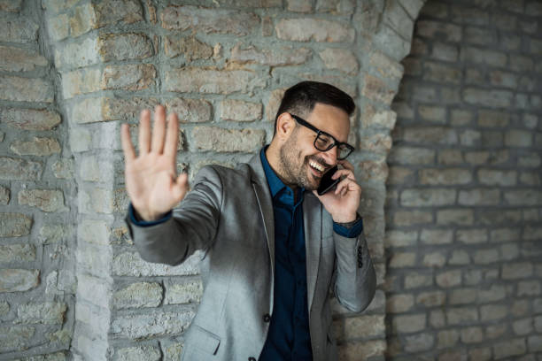 恥ずかしがり屋のビジネスマンが電話で話し、写真を撮りたくないという自発的な写真。 - hand sign stop gesture talking discussion ストックフォトと画像