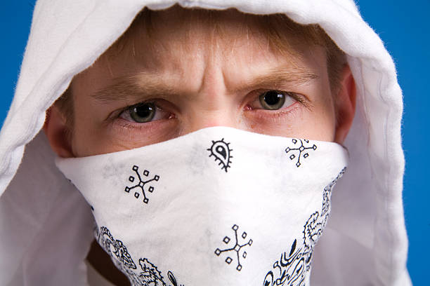 a young teen boy looking mean wearing a bandanna on his face.
