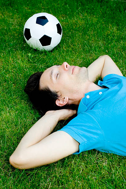 istock Man lying on the grass with soccer ball 146838077