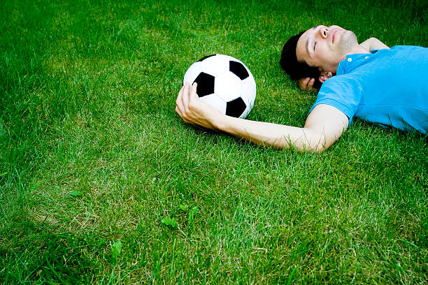 istock Young man lying on the grass with soccer ball 146838082