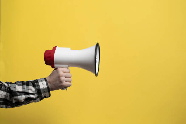 istock Hand holding a loud speaker or megaphone against the monochrome background 1468405376