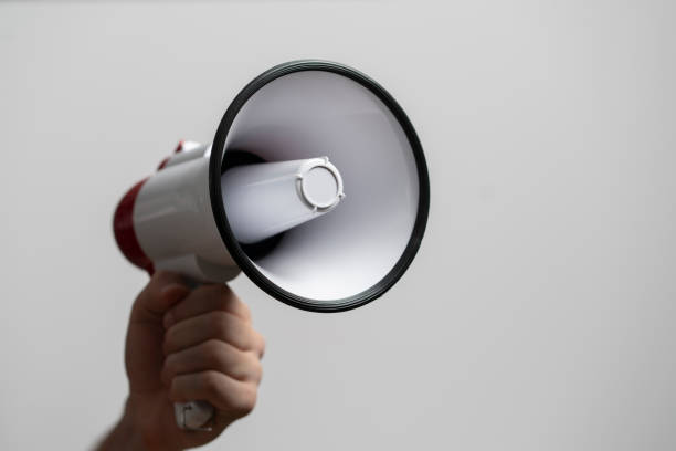 istock Hand holding a loud speaker or megaphone against the monochrome background 1468405387
