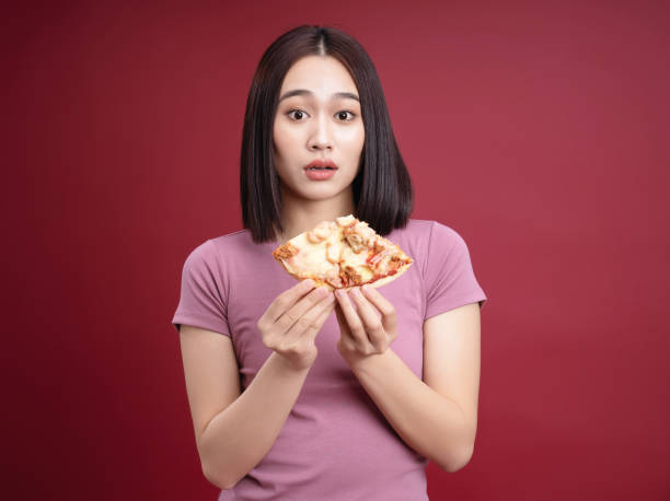 istock Young Asian woman eating pizza on background 1468406944