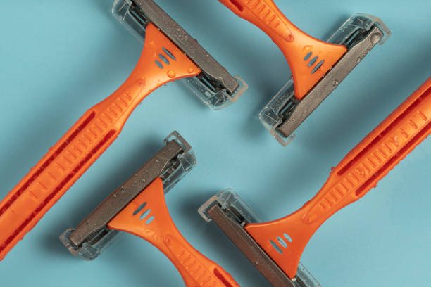 istock Plastic razor on blue background. The concept of using a razor. Razor device. The concept of skin care. Epilation hair removal. Orange men's shaving razors, top view. 1468409032