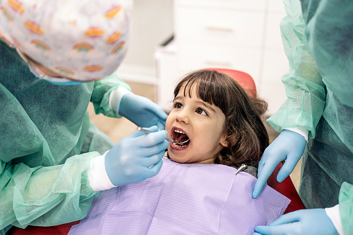 Stock photo of unrecognized professional dental workers doing checkup to a little girl.