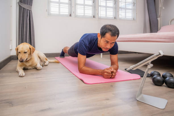 istock Asian man doing plank position to strength training and body core exercises with his dog in bedroom 1468412177