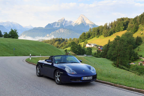 berchtesgaden, alemania - 25 de julio de 2021: roadster azul porsche boxster 986 con watzmann de montaña y panorama de niebla. el coche es un coche deportivo biplaza de motor central fabricado por porsche. - germany landscape nissan roadster fotografías e imágenes de stock