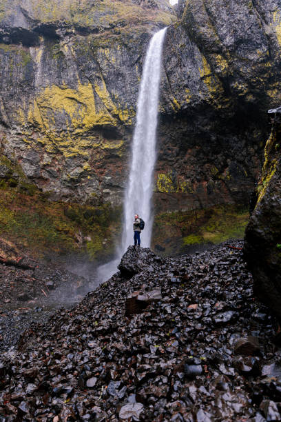 istock Outdoorsman Standing Next To Large Waterfall In Pacific Northwest 1468423418
