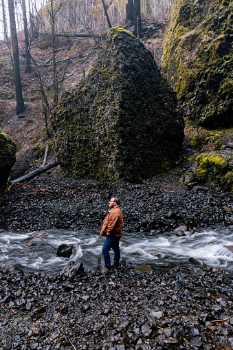 Young caucasian outdoorsman hiking with a backpack in a waterfall area in the Columbia River Gorge in the Pacific Northwest. Taken at Elowah Falls in Oregon.