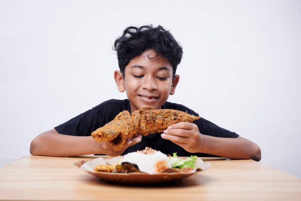 Boy enjoys fried fish and rice at lunch time stock photo