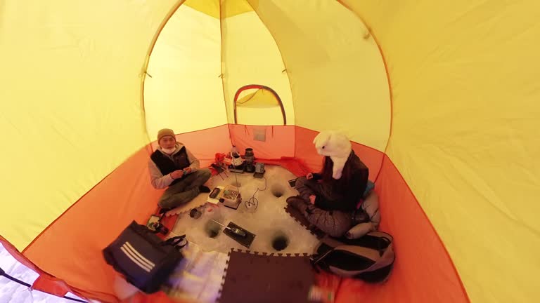 Ice fishing on frozen lake - from underwater up through hole into tent camera movement