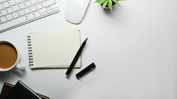 istock Flat lay, top view of blank notepad, cup of coffee, mouse and keyboard on white table. Copy space for your text. 1468428536