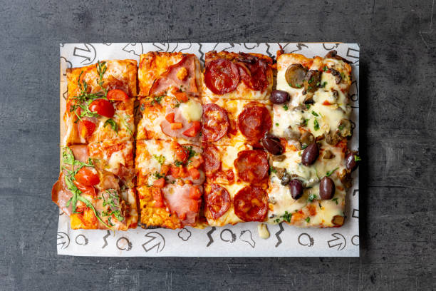 istock Various types of rectangle-shaped pizza slices on a tray 1468428788