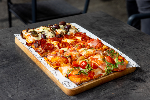 Pizza al taglio on a tray in restaurant, rectangular slices of various types and tastes next to each other
