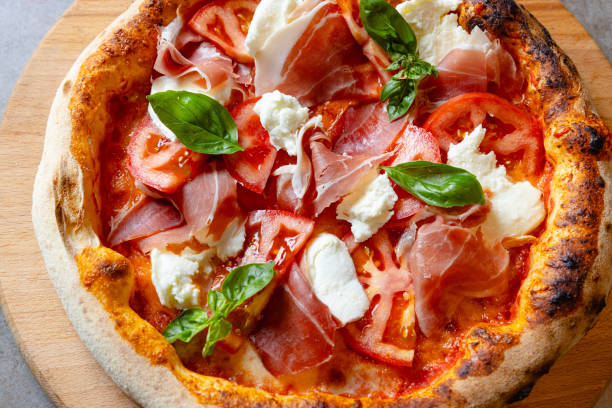 istock Close-up on round pizza with prosciutto, mozzarella and basil 1468428869
