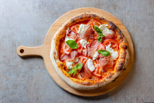 istock Round pizza with prosciutto, mozzarella and basil on wooden board 1468428901