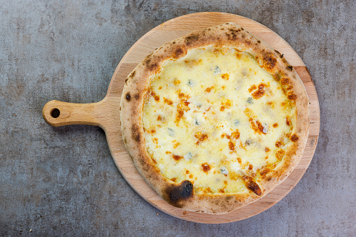 Round baked pizza with predominant cheese topping, Pizza Margherita served on wooden board