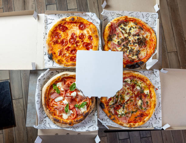 Four different styles of pizza are arranged neatly on wooden trays, showcasing a variety of toppings including cheese, tomatoes, and meats, perfect for a gathering or celebration.