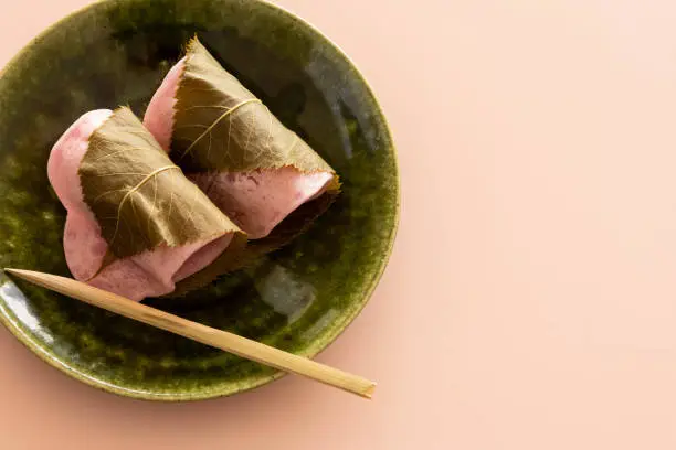 Close-up of sakuramochi on a plate with a pale pink background