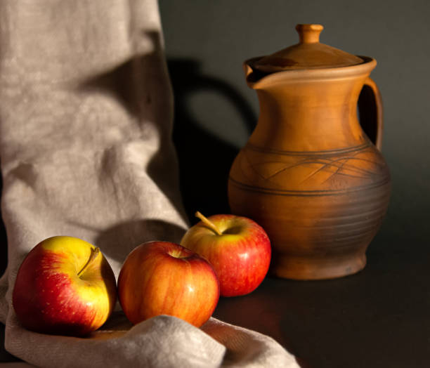 Still life in a rustic style: red apples and a pitcher.