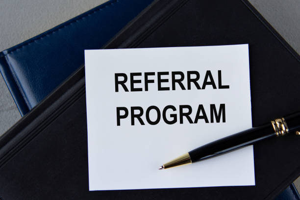 istock REFERRAL PROGRAM - words on white sheet on a black leather book with pen 1468437152