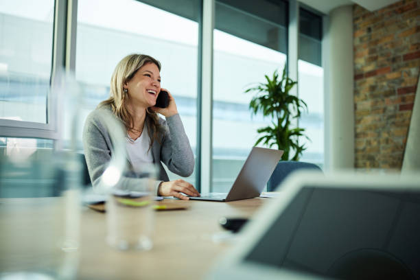 istock Happy businesswoman having a phone call while using laptop in the office. 1468438056
