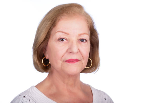 Lady studio headshot over white background. She is serious while turning her left side of her face towards the camera