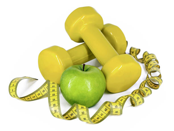 istock green apple between yellow dumbbells and twisted measuring tape isolated on white background, concept of conscious lifestyle with sport and healthy eating 1468443011