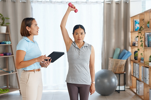 Arm physiotherapy, dumbbell or senior Asian woman with support help on recovery rehabilitation or motion training. Physical therapy portrait or physiotherapist helping healthcare patient with fitness