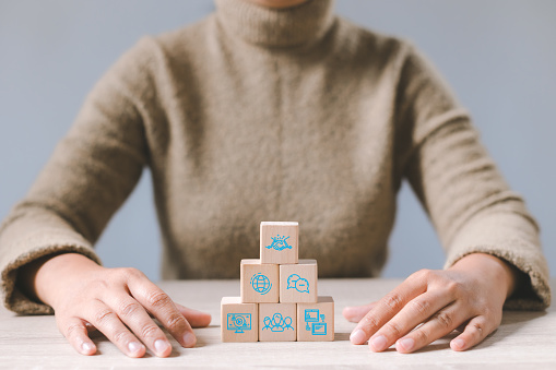 Businesswoman with wood cube block stacking about global business cooperation icon. Online business communications and network technology concept.