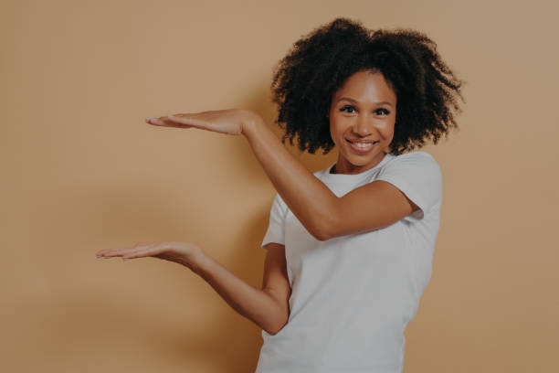 istock Young dark skinned showing large object, shaping box with both hands, isolated over beige background 1468451137